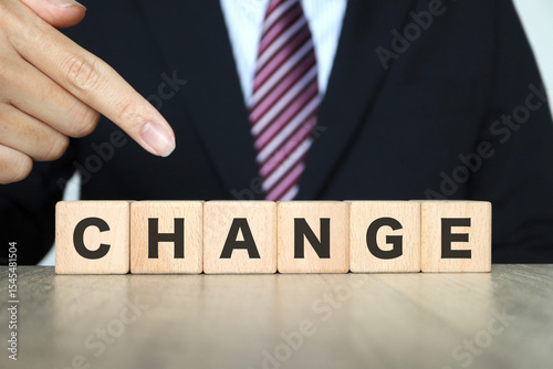 CHANGEと書かれた木のブロックを指し示すビジネスマンの手元