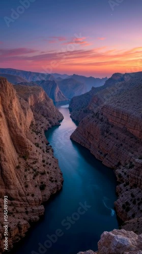 Sunrise illuminates a deep canyon with a river and boat, timelapse