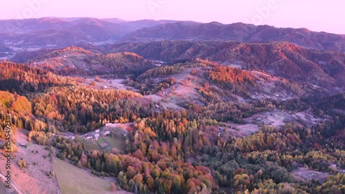 Ukraine, drone, flight in the Carpathians early in the autumn morning at sunrise near the city of Kosiv. Bright forests and dwellings of the Hutsul highlanders on the glades