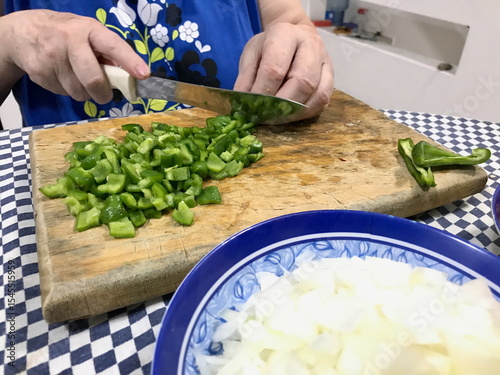 Elderly Woman Slicing Green Peppers on Wooden Board