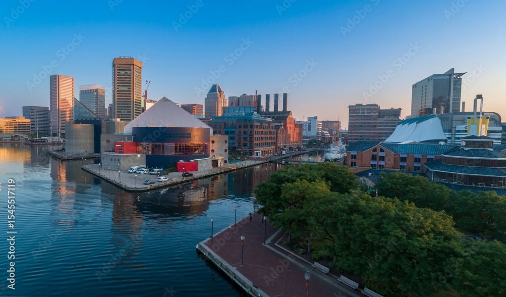Obraz premium Aerial view of Baltimore's Inner Harbor, Maryland, USA, showcasing the city's skyline and waterfront attractions. A lone person walks along the pier.