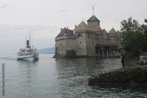 cloudy Chillon Castle over the lake in Montreaux with a ship docking, Switzerland
