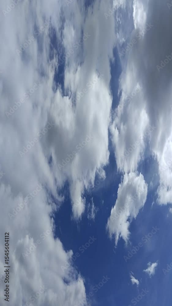 Un cielo de azul con varias nubes de color blanco y gris con un movimiento lento. Video vertical