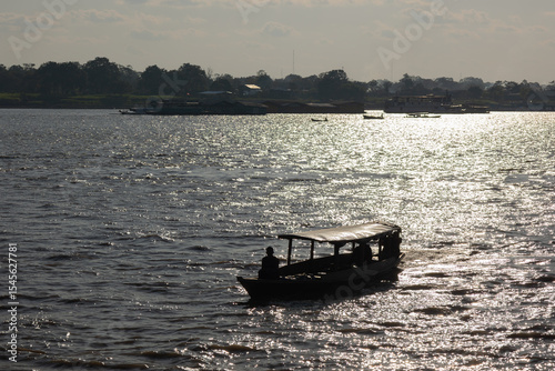 Silhouette of Amazon riverboat cruising at sunset with shimmering water