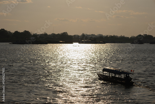 Covered Amazon riverboat cruising at sunset with Peruvian flag