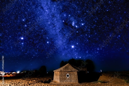 Desert hut under a brilliant starry night sky.