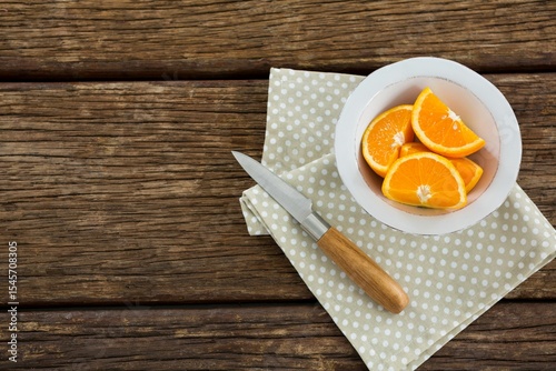 Orange slices in bowl with knife and napkin on table