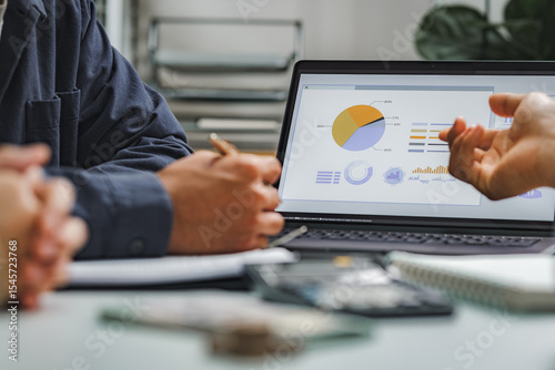 Business professionals analyzing sales data on computer screen with charts and graphs for strategic planning and performance evaluation.