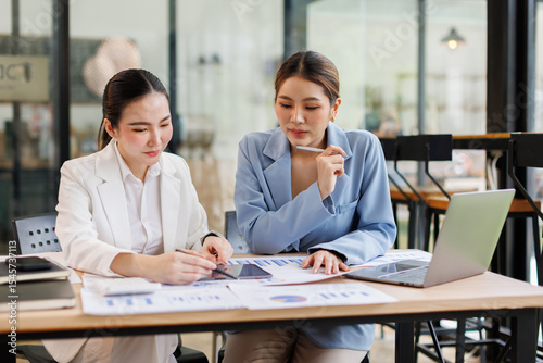 Portrait of Two casual asian business women at work.doing planning analyzing the financial report, business plan investment, finance analysis concept	
