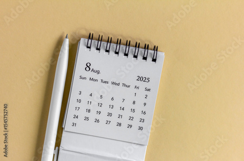 Hello, August 2025. Desktop calendar for planning on a beige background with a copy of space.