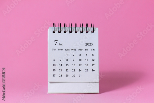 Hello, July 2025. Desktop calendar for planning on a pink background with copy space.