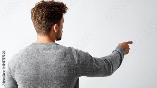 A man in a gray sweater pointing at something
