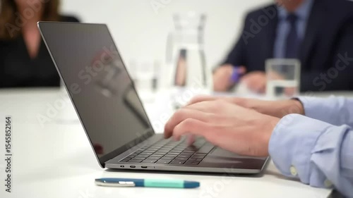 Hands typing on a laptop in a modern office