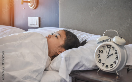 Sleepless girl child suffering sleep disorder, insomnia problem, mental health illness. Young asian school kid, keeping awake with anxiety or nightmare fear on bed at late night in home bedroom