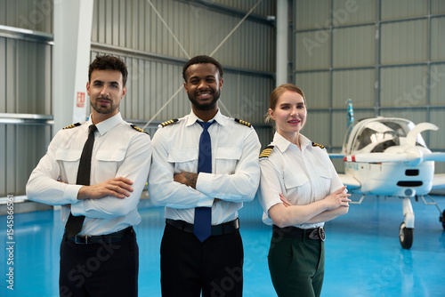 Photos Confident student pilots posing in aircraft hangar
