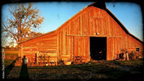Rustic red barn with open doors in the countryside during golden hour