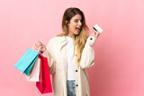 Young woman with shopping bag isolated on pink background holding shopping bags and a credit card