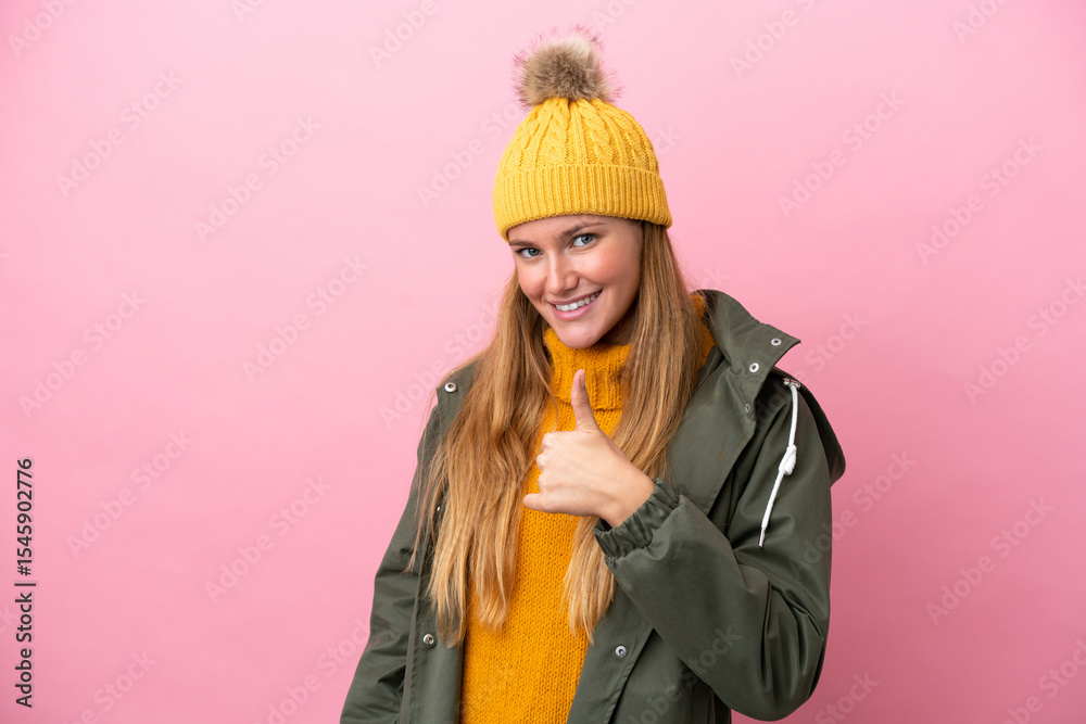 Young blonde woman wearing winter jacket isolated on pink background giving a thumbs up gesture Young blonde woman wearing winter jacket isolated on pink background giving a thumbs up gesture