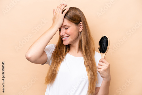 Young pretty blonde woman with hair comb isolated on beige background has realized something and intending the solution