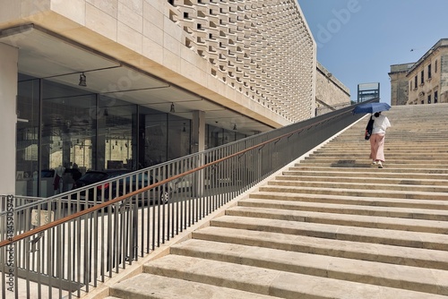 Female tourist climbing up the wide stairs with a sun umbrella