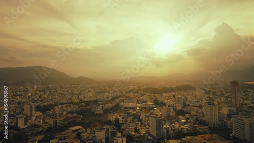 A beautiful golden sunset casts a vibrant glow over an urban landscape with majestic mountains