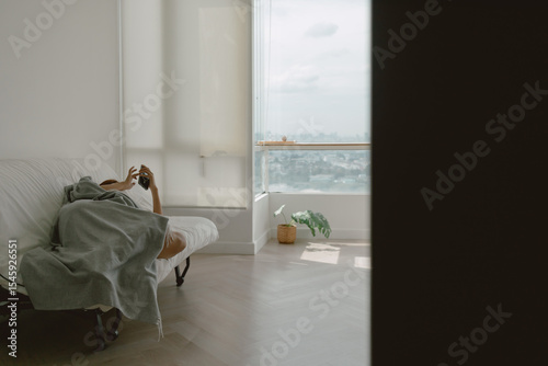 Woman taking a nap using phone in her apartment on weekends.