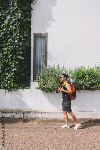 Tourist backpacker walking on the street passing white hotel building.