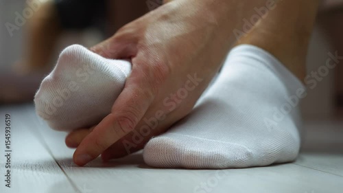 Man touching his sore foot in socks.
Fatigue of feet or foot injury.
Sore foot in white socks