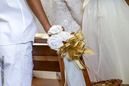 Détail de décoration florale dorée et blanche sur un banc d’église pour une cérémonie religieuse