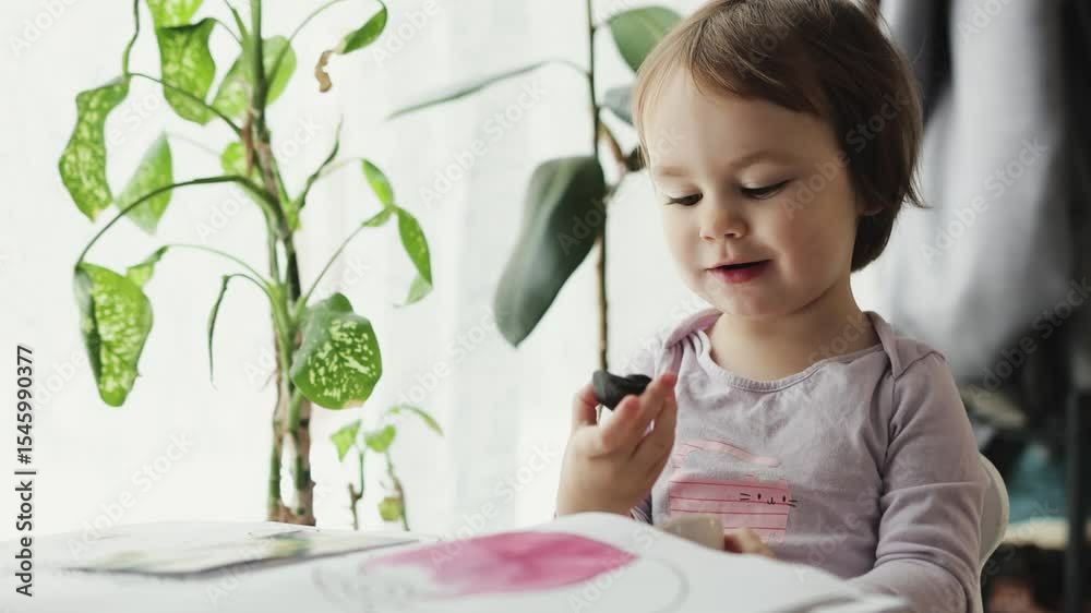 A child plays with plasticine and enthusiastically shows what she has created, creativity, activities with plasticine at home.