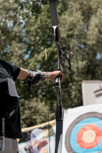 Archer Aiming Compound Bow at Target with Blurred Background, Outdoor Sport, Black Equipment, Red Bullseye, Sunny Day, Archery Practice Shot