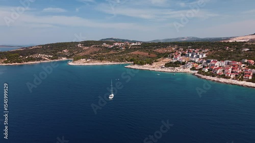 Aerial view of Croatian coastline with yacht sailing near seaside village and islands. Travel and summer holidays concept