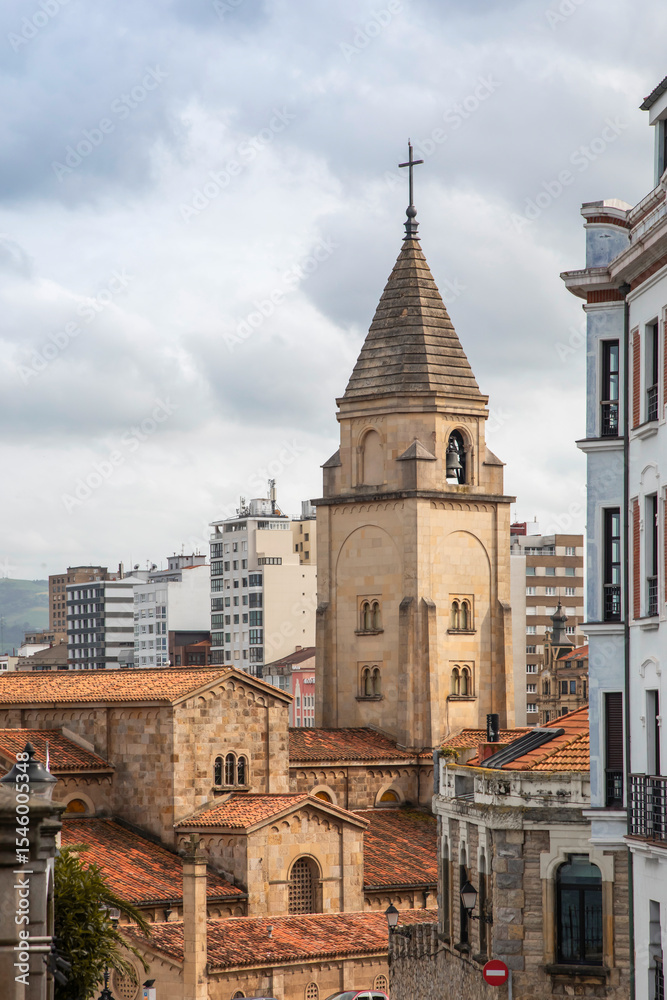 Fototapeta premium Gijon city view, Historic church tower in an urban cityscape under a cloudy sky. Asturias, Spain