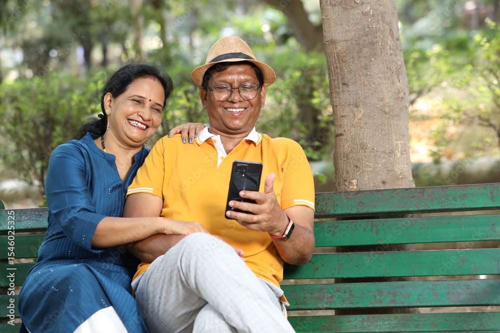 Obraz premium Indian senior happy couple using mobile phone at the park.