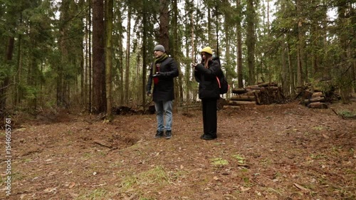couple makes their way through a forest with sparse trees and muted tones, representing environmental mindfulness and seasonal travel.