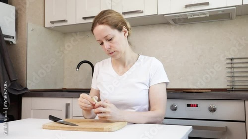 Woman peeling garlic in the kitchen, domestic food preparation at home, healthy meal for modern nutrition.