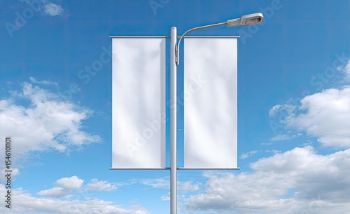 Two blank white vertical banners hang from a streetlight pole against a partly cloudy blue sky