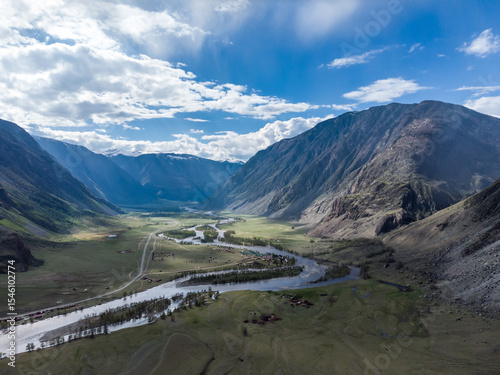 Scenic view of Chulyshman River Valley in Altai. lush green vegetation and towering mountains under cloudy sky. Travel and landscape photography.