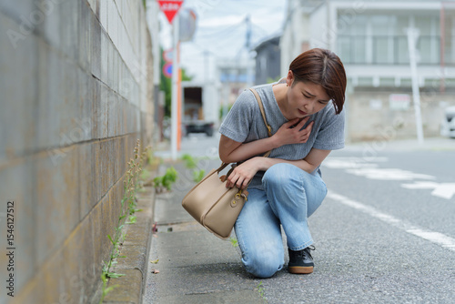 体調不良でうずくまる女性