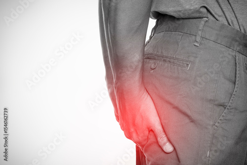 Man clutching buttocks in pain with red spot highlight, concept of hemorrhoids or anal discomfort, isolated on white background.