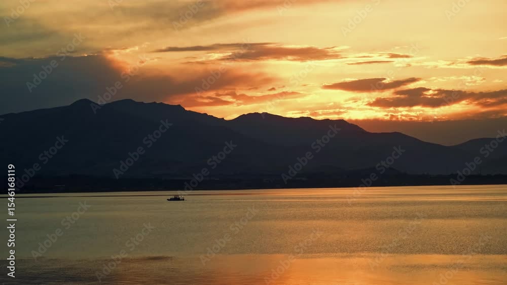 Golden Sunset Cruise with Tour Boat on Tranquil Lake and Mountain Silhouettes Golden Sunset Cruise with Tour Boat on Tranquil Lake and Mountain Silhouettes