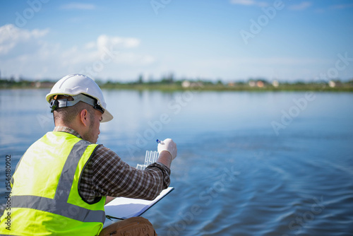 A specialist engineer at a treatment pond is checking the water quality of the treated pond.