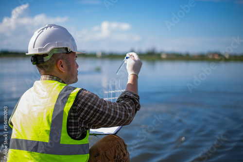 A specialist engineer at a treatment pond is checking the water quality of the treated pond.