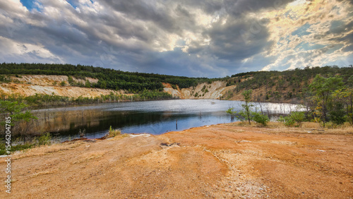 Scenic view of the Radka Mine in Bulgaria – a former open-pit copper mine now filled with water. Surrounded by hills and clouds, the site reflects nature reclaiming an industrial landscape.