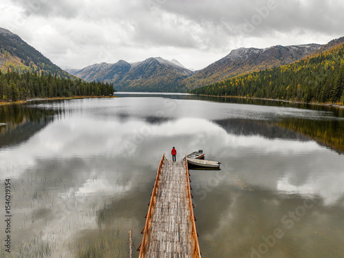 Canvas-taulu A person stands on a wooden pier, gazing out at the expansive Rakhmanovskoe Lake