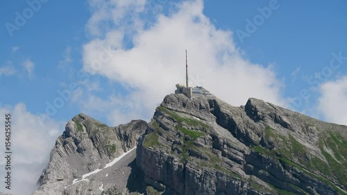 Mountain peak with communication tower and cloudy sky in the background during daylight hours