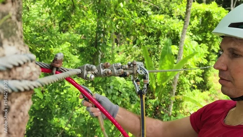 A man is enjoying an exhilarating ride on a zip line that traverses the thick woods surrounding him