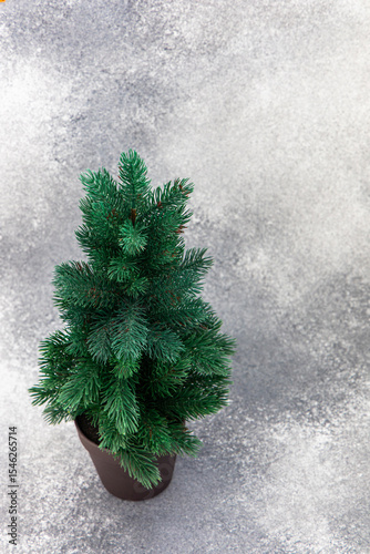 Decorative artificial tree in a brown pot displayed on a textured gray background