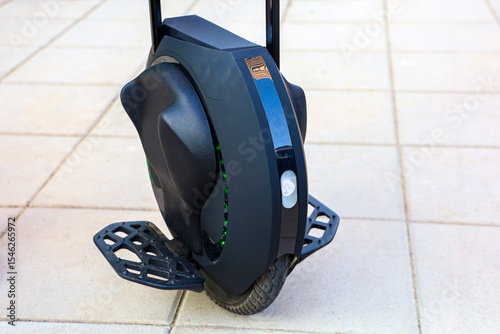 Modern electric unicycle parked on concrete pavement in bright daylight