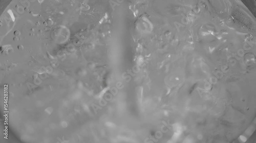 スーパースロー映像：夏の自然の中で、氷が入ったガラスのコップに炭酸水を注ぐ様子